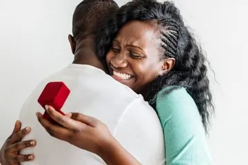 woman embracing a man holding a ring box