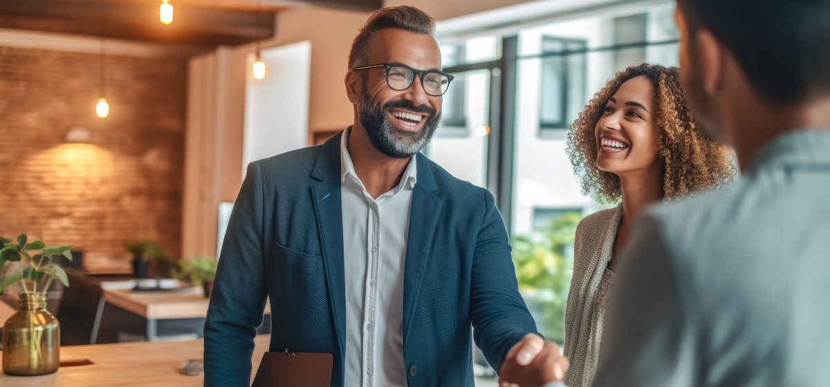 two men shaking hands with a woman standing nearby