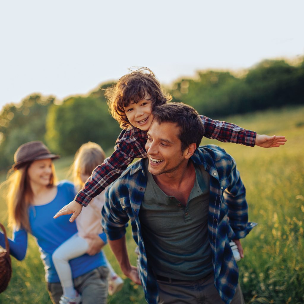 father with son on his shoulders in a field